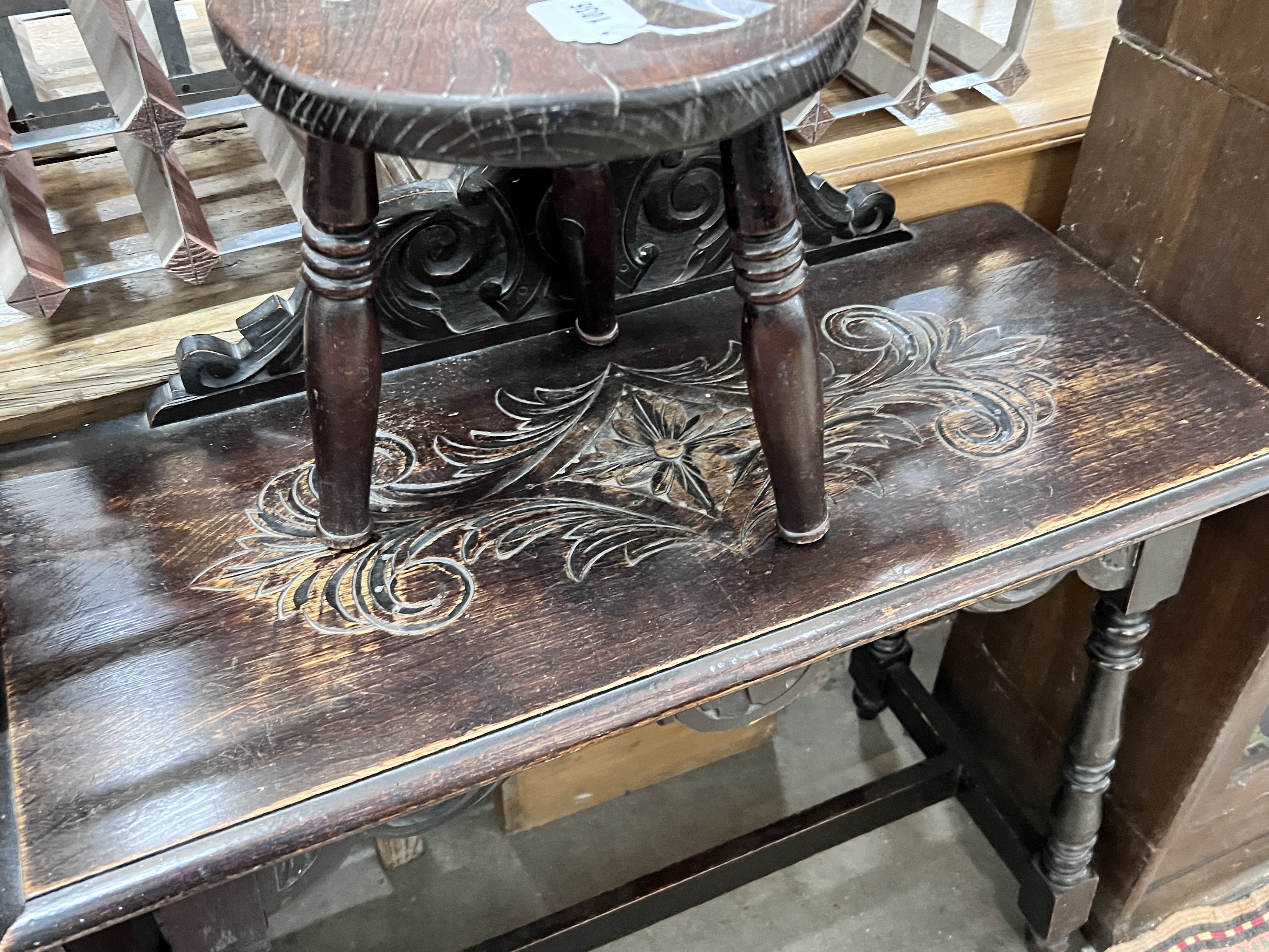 An early 20th century carved oak open bookcase, width 92cm, depth 26cm, height 114cm, together with a carved oak table and circular stool